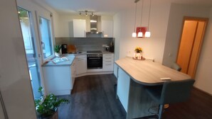 A modern kitchen with white cabinetry, a built-in oven, and a wooden countertop. - New comfort apartment. Basement, good for excursions, Europapark, Strasbourg (Ortenberg)