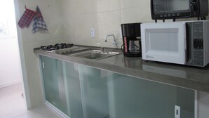 Een keuken met een gasfornuis, een koffiezetapparaat en twee magnetrons.