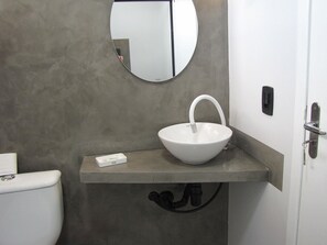 Et badeværelse med en hvid vask, et spejl og et toilet.