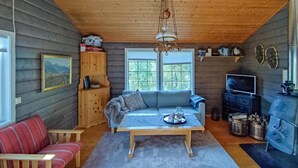 L’intérieur chaleureux d’un chalet avec un canapé, une table sur laquelle est posé un plateau, un téléviseur et une cheminée.