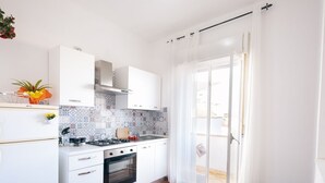 Una cocina moderna con armarios blancos, salpicadero de azulejos, estufa a gas y horno empotrado.