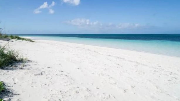Een strand met wit zand en een helderblauwe lucht.