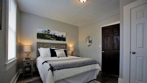 Ein Schlafzimmer mit Bett, Nachttischen, Spiegel und Tür.
