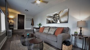 Ein modernes Wohnzimmer mit einem grauen Sofa, zwei runden Couchtischen, einer Lampe und einem Gemälde an der Wand.