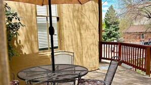 Eine Terrasse im Freien mit Tisch und Stühlen, einem großen Sonnenschirm und einem Holzboden.