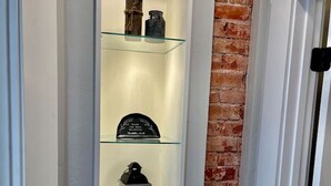 A narrow hallway with a glass display case containing decorative items. - Manitou Apartment 2B (Manitou Springs)