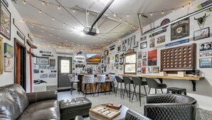 A cozy room with leather furniture, a bar area, and various wall decorations. - Après 4 All | Game Room, Hot Tub, Walkable (Ellicottville)