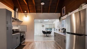 Een moderne keuken met grijze kastjes, een roestvrijstalen koelkast en een houten plafond.
