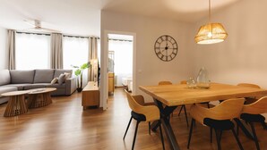 Un salon moderne comprenant un canapé, une table basse, une table à manger avec des chaises et une grande horloge murale.