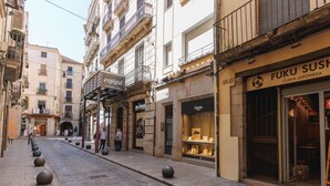 A cobblestone street lined with buildings, including a sushi restaurant and a store named 'espigul'.