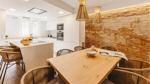 A modern kitchen with white cabinets, a central island, and a stone accent wall.