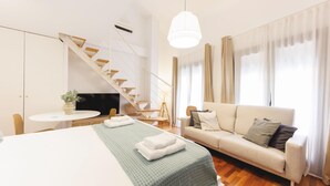 Une pièce moderne et bien éclairée, comprenant un lit, un canapé, une table à manger et un escalier.