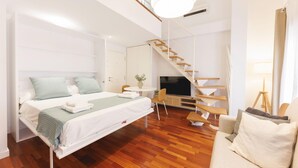 Une chambre d’hôtel moderne équipée d’un lit, d’un canapé, d’une télévision, d’un escalier et d’un coin repas.