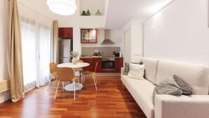 Un salon moderne avec un canapé et une table à manger entourée de chaises. On y trouve également un coin cuisine avec des placards et une cuisinière.