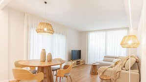 Un salon moderne avec une table de salle à manger ronde en bois, deux chaises, un canapé et un téléviseur.