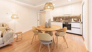 Une cuisine moderne avec des meubles blancs, une table de salle à manger ronde en bois et un four encastré.
