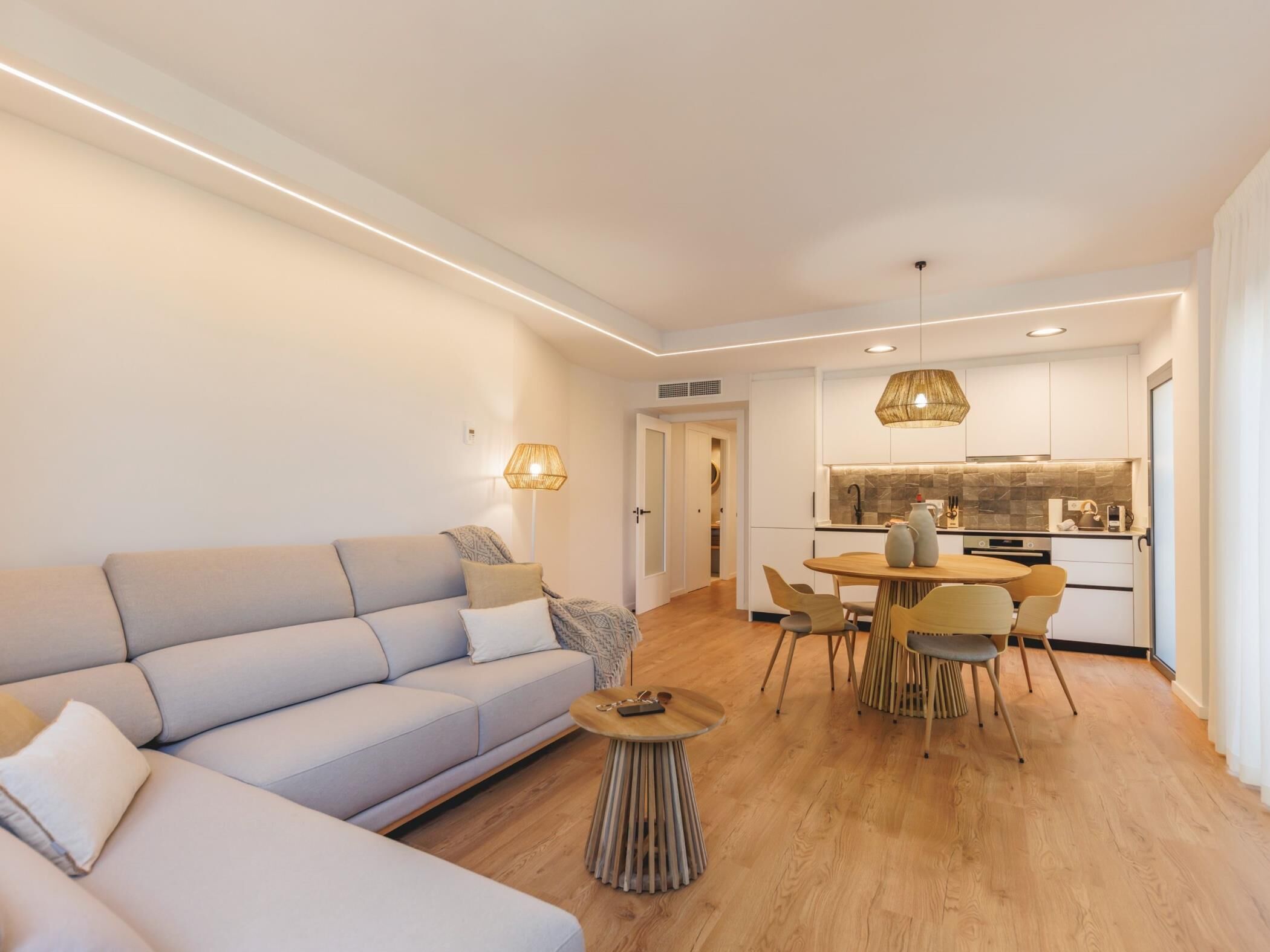 Un salon moderne comprenant un canapé, une table basse et un coin repas avec des chaises et une table.
