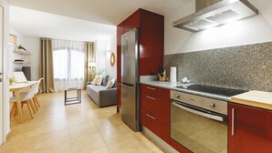 A modern kitchen with red cabinets, a stainless steel refrigerator, and a granite countertop. - Bravissimo Plaça Catalunya, apartment with terrace (Girona)