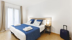 A hotel room with a bed, a nightstand, a lamp, and a suitcase. - Bravissimo Plaça Catalunya, apartment with terrace (Girona)