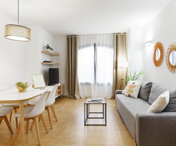 Una sala de estar moderna con comedor, un sofá, un televisor y una mesita.