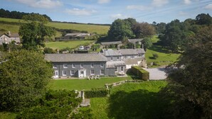 Une grande maison en pierre avec une vaste pelouse et une allée.