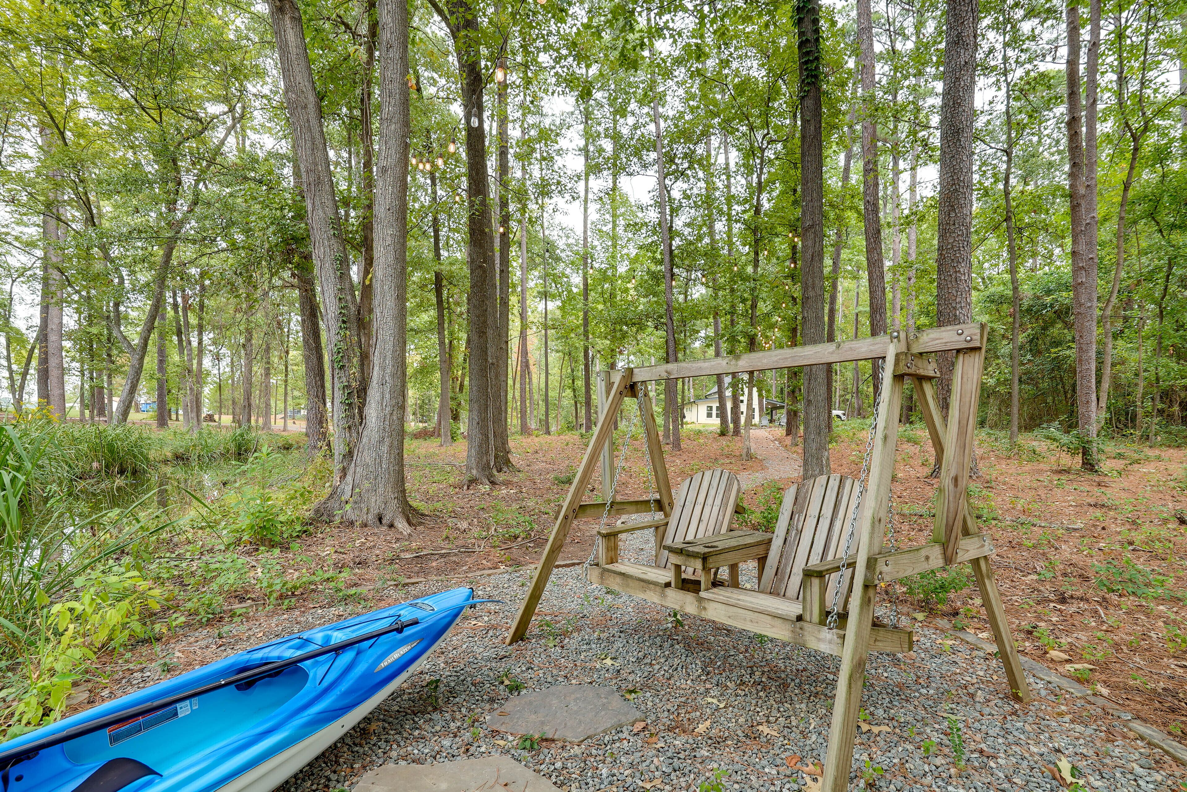 A wooden swing set in a forested area with a blue kayak nearby.