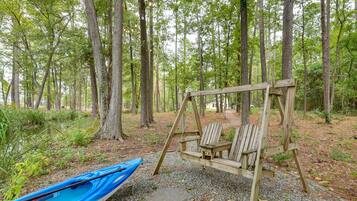 A wooden swing set in a forested area with a blue kayak nearby.