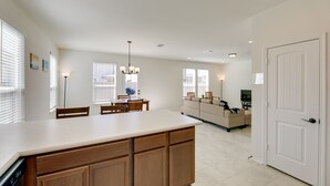 Eine moderne Küche mit Kochinsel, Essbereich mit Stühlen, einem Sofa und einem Fernseher im Wohnzimmer.