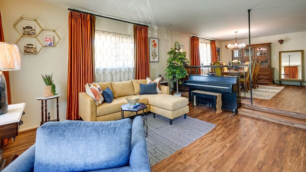 A living room with a beige sofa, a blue armchair, a piano, and a dining area with a wooden table and chairs. - Close to Wine & Outdoors! Vallejo Vacation Rental (Vallejo)