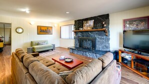 A living room with a stone fireplace, a large flat-screen TV, and a sectional sofa. - Close to Wine & Outdoors! Vallejo Vacation Rental (Vallejo)