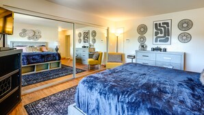 A bedroom with a large mirror, a bed with a blue blanket, a dresser, and a chair. - Close to Wine & Outdoors! Vallejo Vacation Rental (Vallejo)