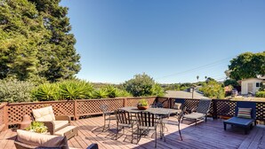A wooden deck with outdoor furniture, including a table and chairs, surrounded by a wooden fence and lush greenery. - Close to Wine & Outdoors! Vallejo Vacation Rental (Vallejo)