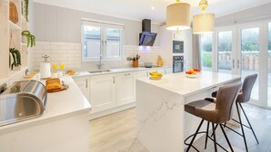 Una cocina moderna con armarios blancos, una isla de mármol e iluminación colgante.