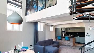A modern interior with a dining area, a large abstract painting, a staircase, and a kitchen.