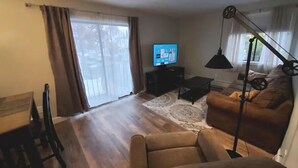 A living room with a sofa, a television, a lamp, and a dining table.