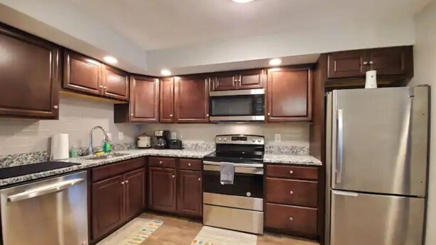 A modern kitchen with dark wooden cabinets, stainless steel appliances, and a granite countertop.