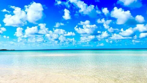 A beach with clear turquoise water and a bright blue sky with scattered clouds. - Jasmine-On the Harbour, Minutes from the Beach (Spanish Wells)