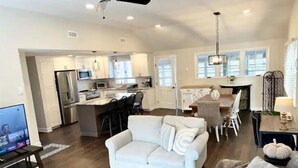A spacious living area with a white sofa, a dining table with chairs, a kitchen area with a refrigerator and microwave, and a ceiling fan. - Charming Home in Reading with a Large Yard (Reading)