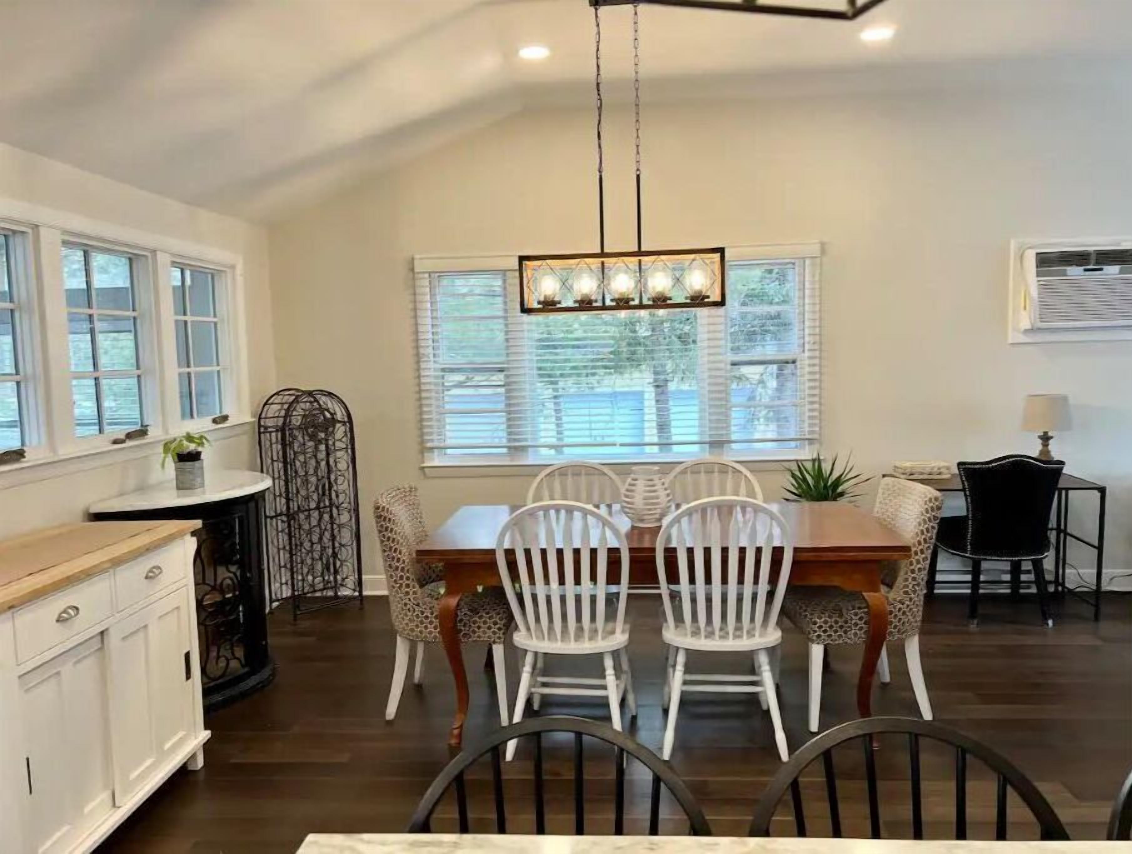 A dining area with a wooden table, white chairs, and a chandelier.