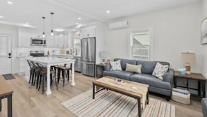 A modern kitchen with white cabinets, stainless steel appliances, and a central island with bar stools.