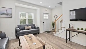 A modern living room with a grey sofa, wooden coffee table, and a staircase leading to another level.
