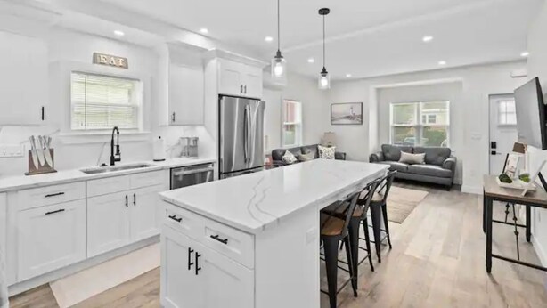 A modern kitchen with white cabinetry, a central island, and pendant lighting.
