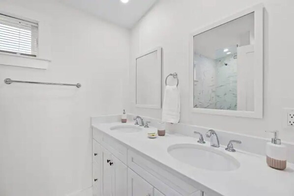 A modern bathroom with two sinks, a large mirror, and a towel rack.