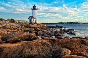A lighthouse on a rocky shore with a wooden walkway leading to it.