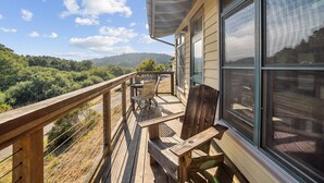 A wooden deck with outdoor furniture, a railing, and a view of a forested landscape. - Limantour Lodge-Laguna House-Perfect for Families! (Point Reyes Station)