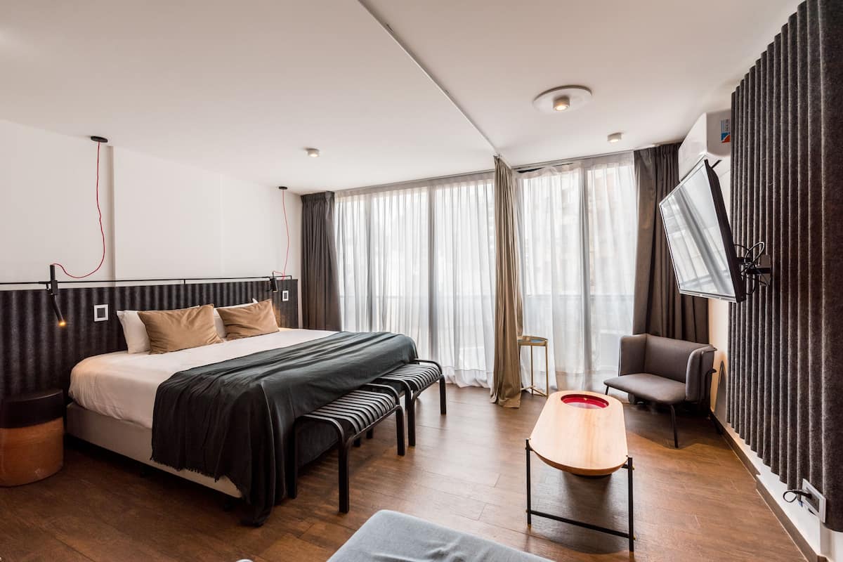 Une chambre d’hôtel moderne, dotée d’un grand lit, d’un bureau, d’une chaise et d’un téléviseur fixé au mur.