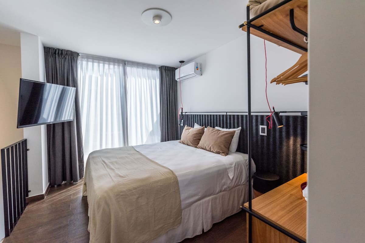 Une chambre d’hôtel équipée d’un lit, d’une télévision, d’un radiateur et d’un porte-manteau.