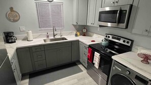 Een moderne keuken met een spoelbak, fornuis, magnetron en oven.