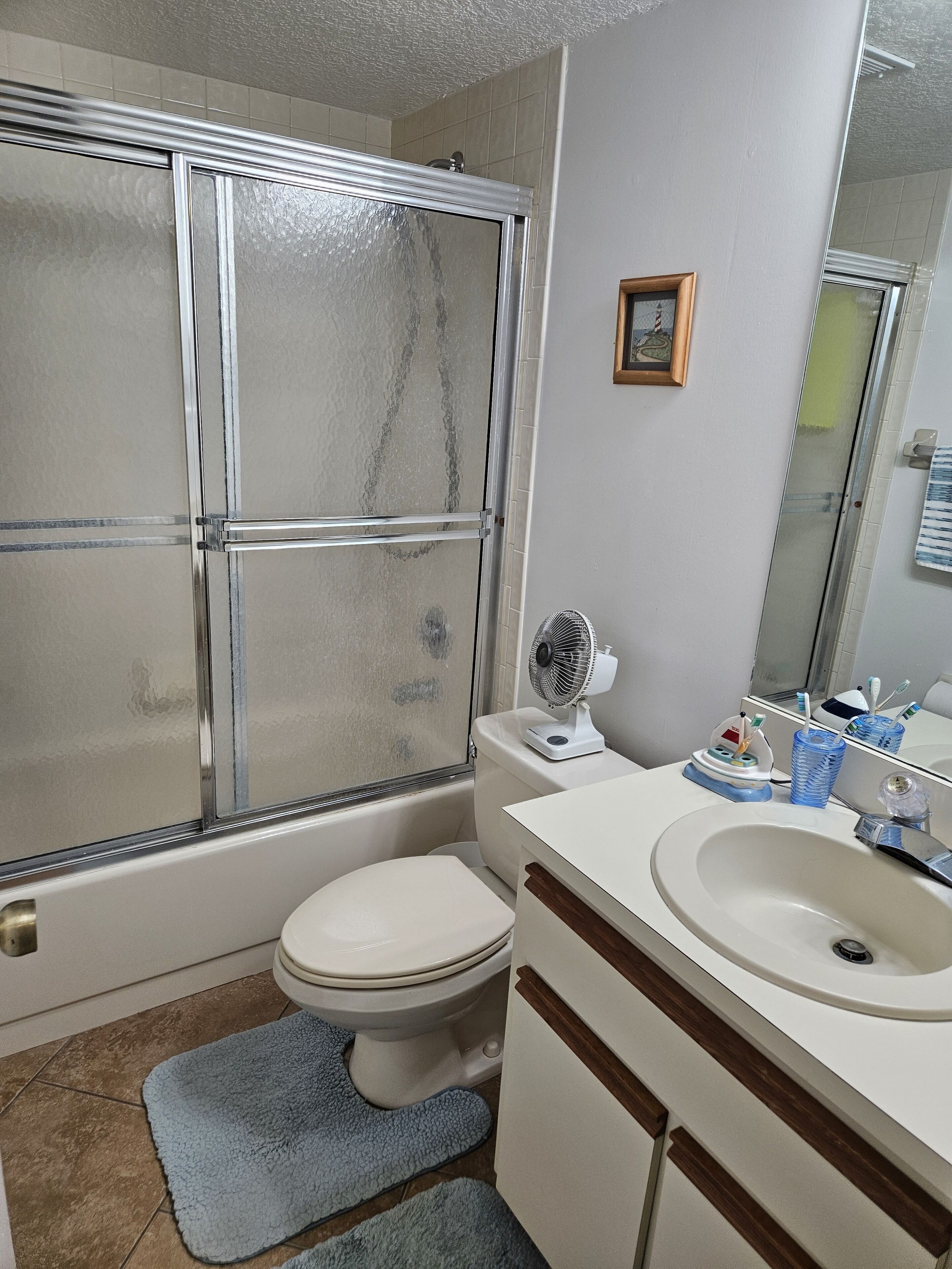 Un baño con ducha, inodoro, lavabo y espejo.