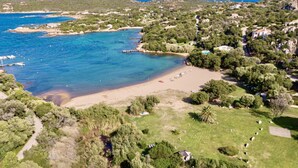 Ett flygbildsbild av ett kustområde med en strand, klart blått vatten och omgivande grönska.
